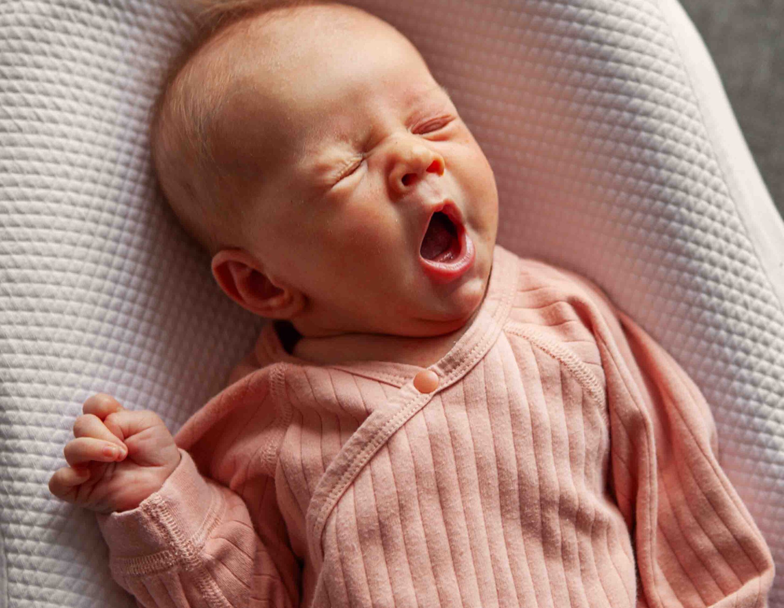 Neonato che sbadiglia e appare irrequieto, simbolo di insonnia e difficolt&agrave; nel sonno trattabili con osteopatia pediatrica