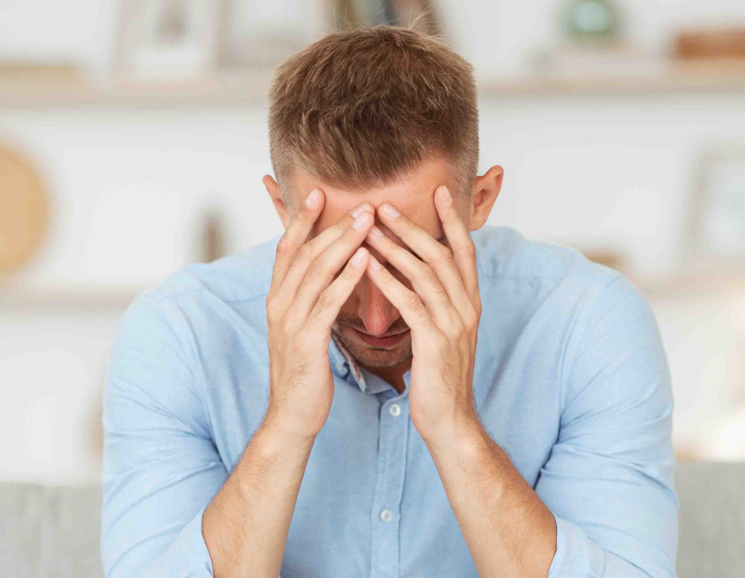 Uomo seduto con le mani sul volto, espressione di ansia e stress