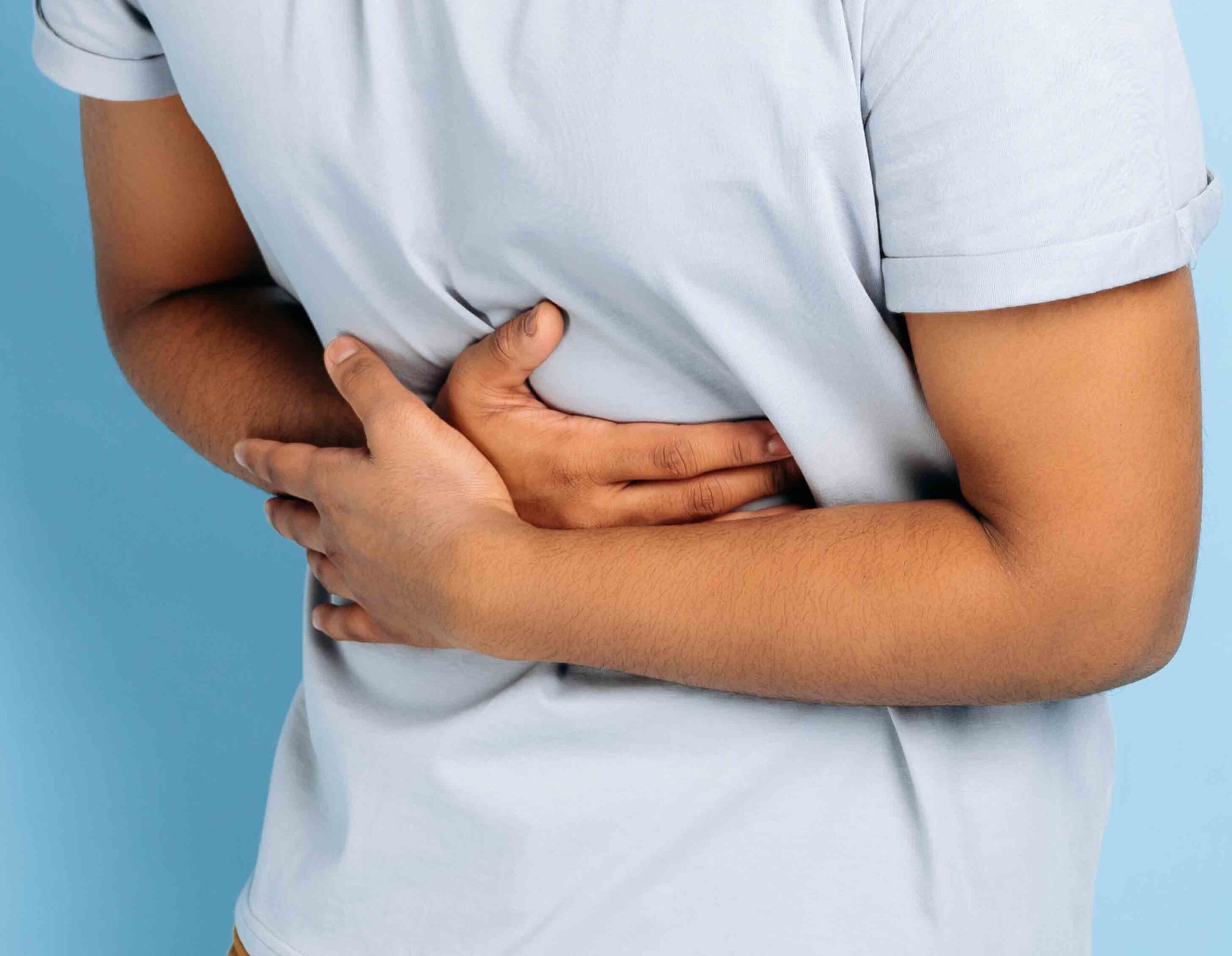 Uomo con dolore addominale che si tiene la pancia, sintomo di stitichezza e irregolarit&agrave; intestinale