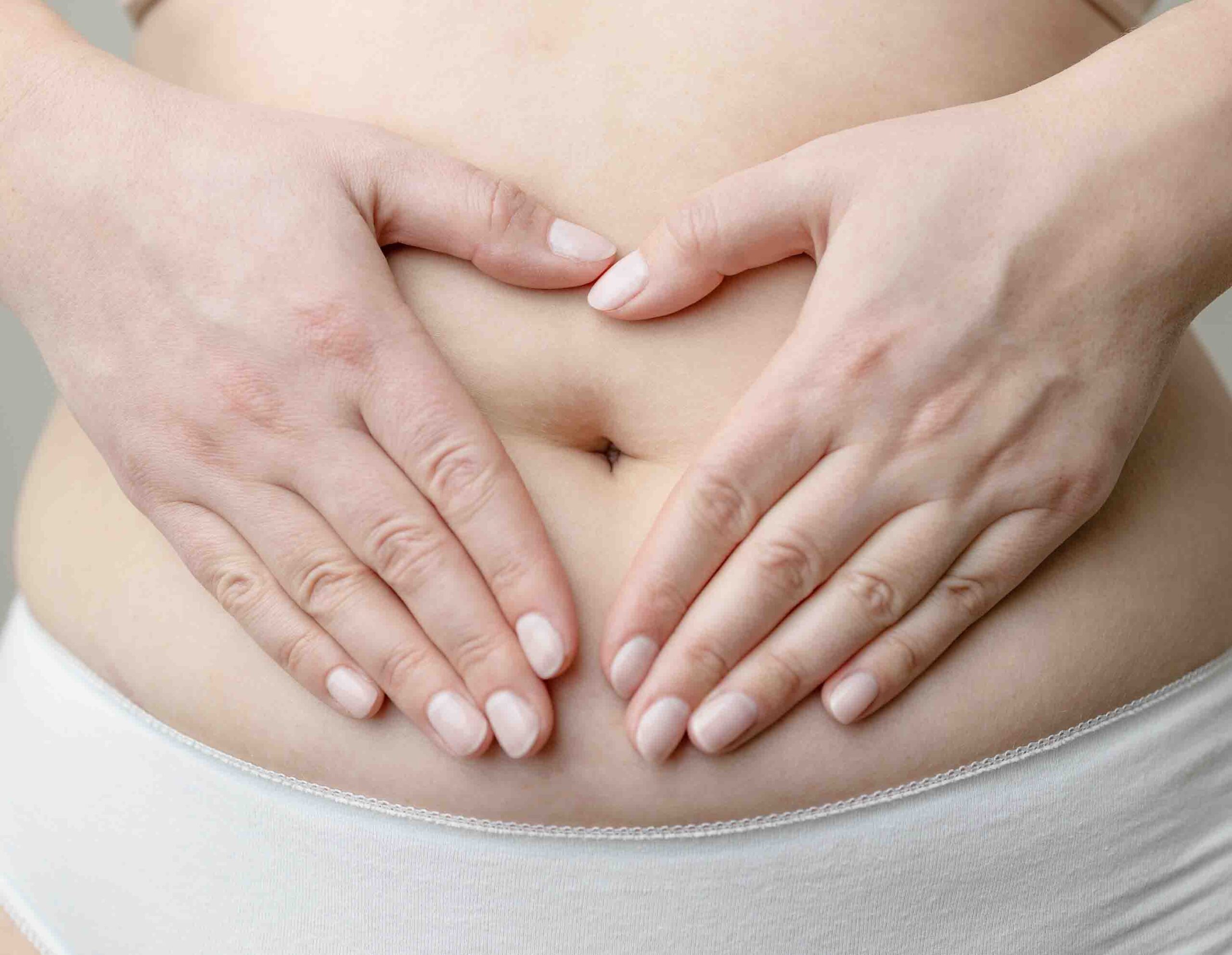 Donna che si tocca l&rsquo;area pelvica con le mani a cuore, simbolo di dolore e disagio femminile