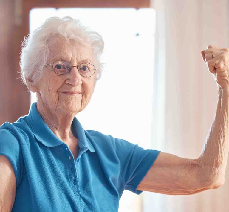 Donna anziana sorridente che mostra forza, benefici dell&rsquo;osteopatia geriatrica a Roma